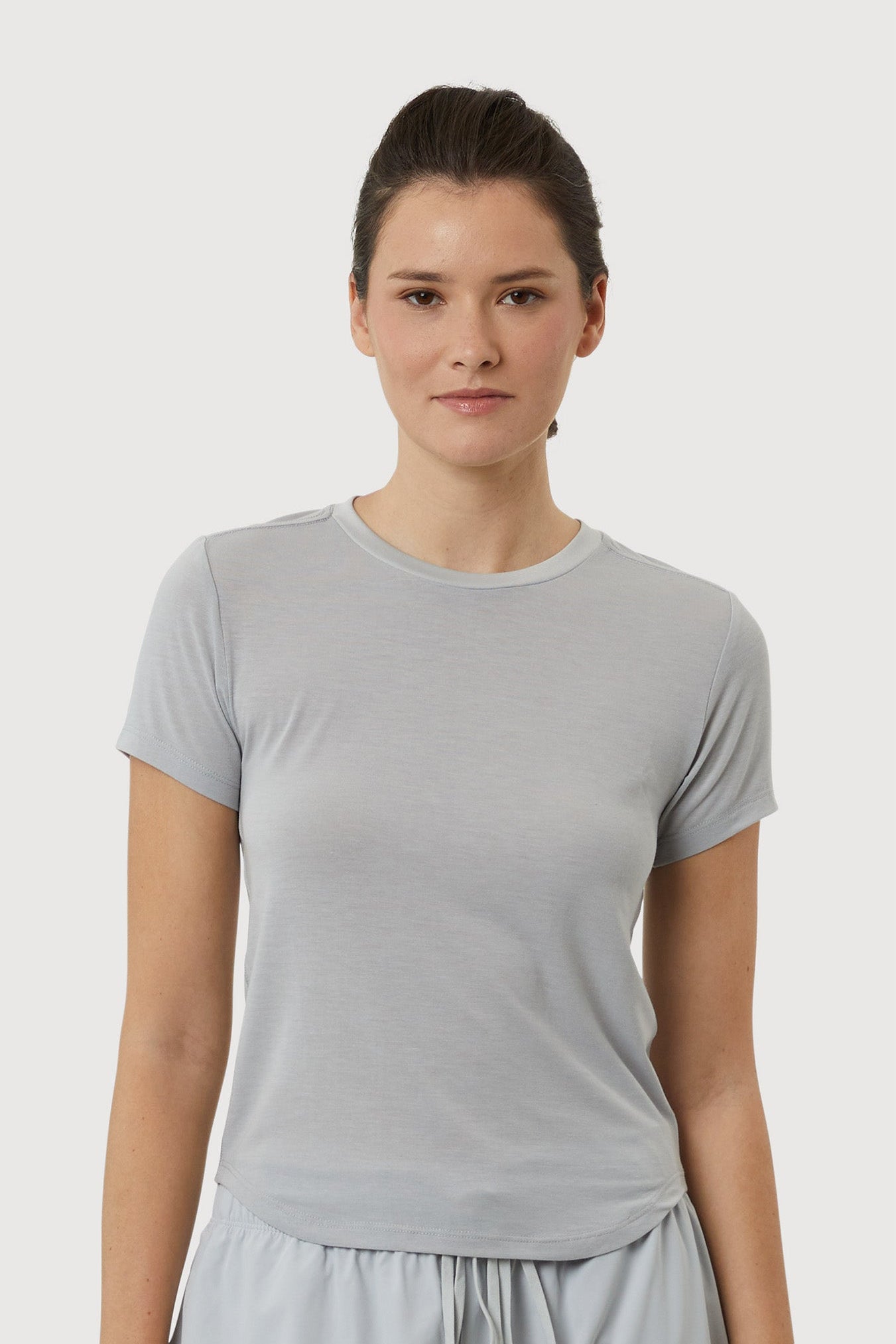 Woman wearing a light gray t-shirt and pants on a white background