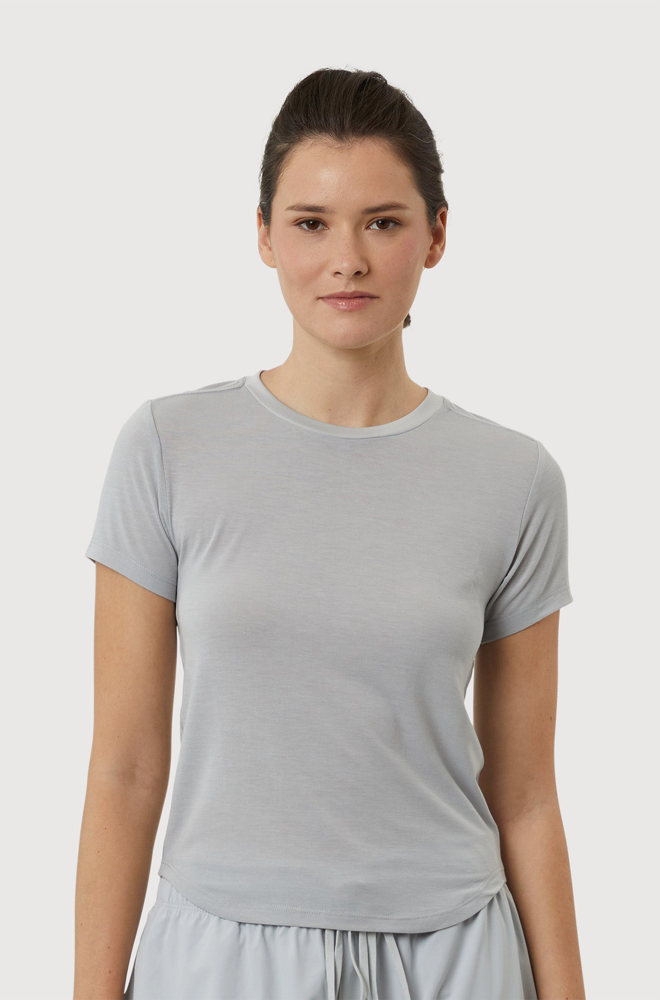 Woman wearing a light gray t-shirt and pants on a white background