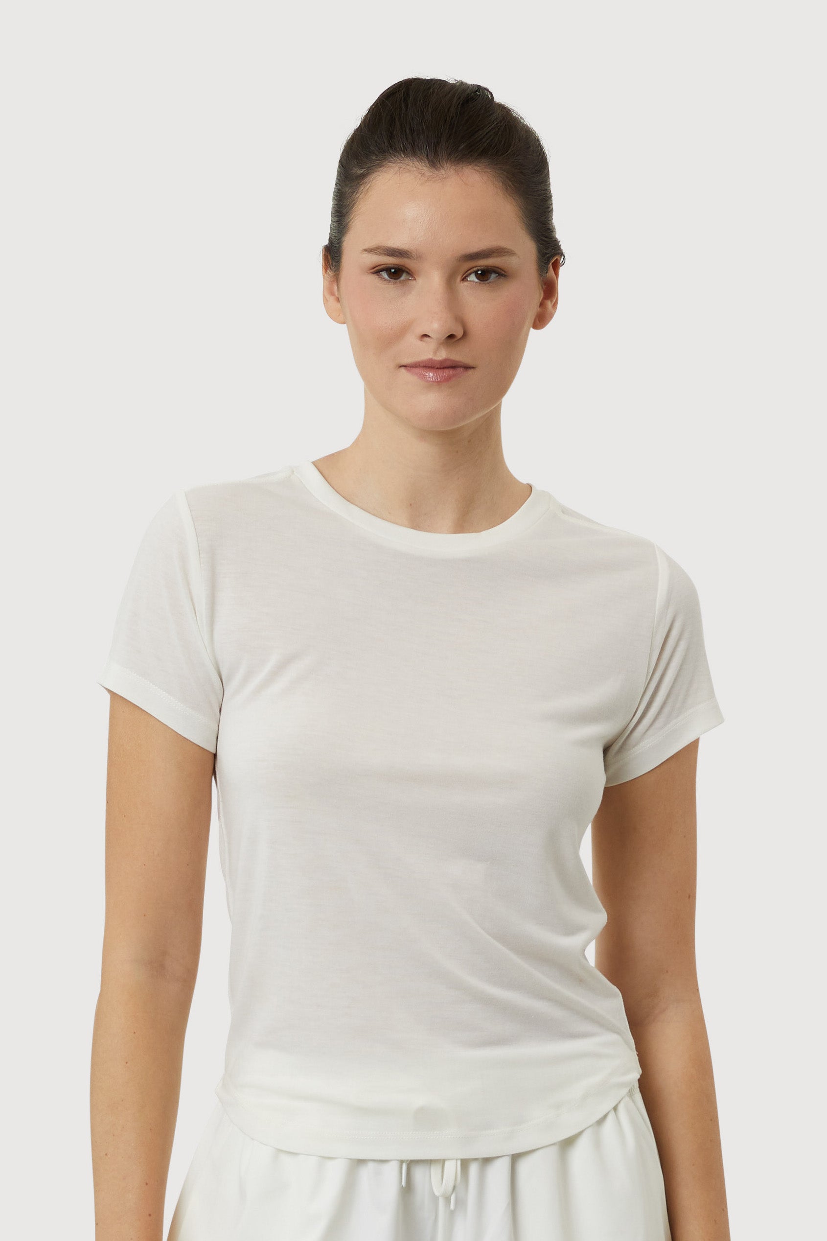 Woman wearing a plain white t-shirt against a light gray background