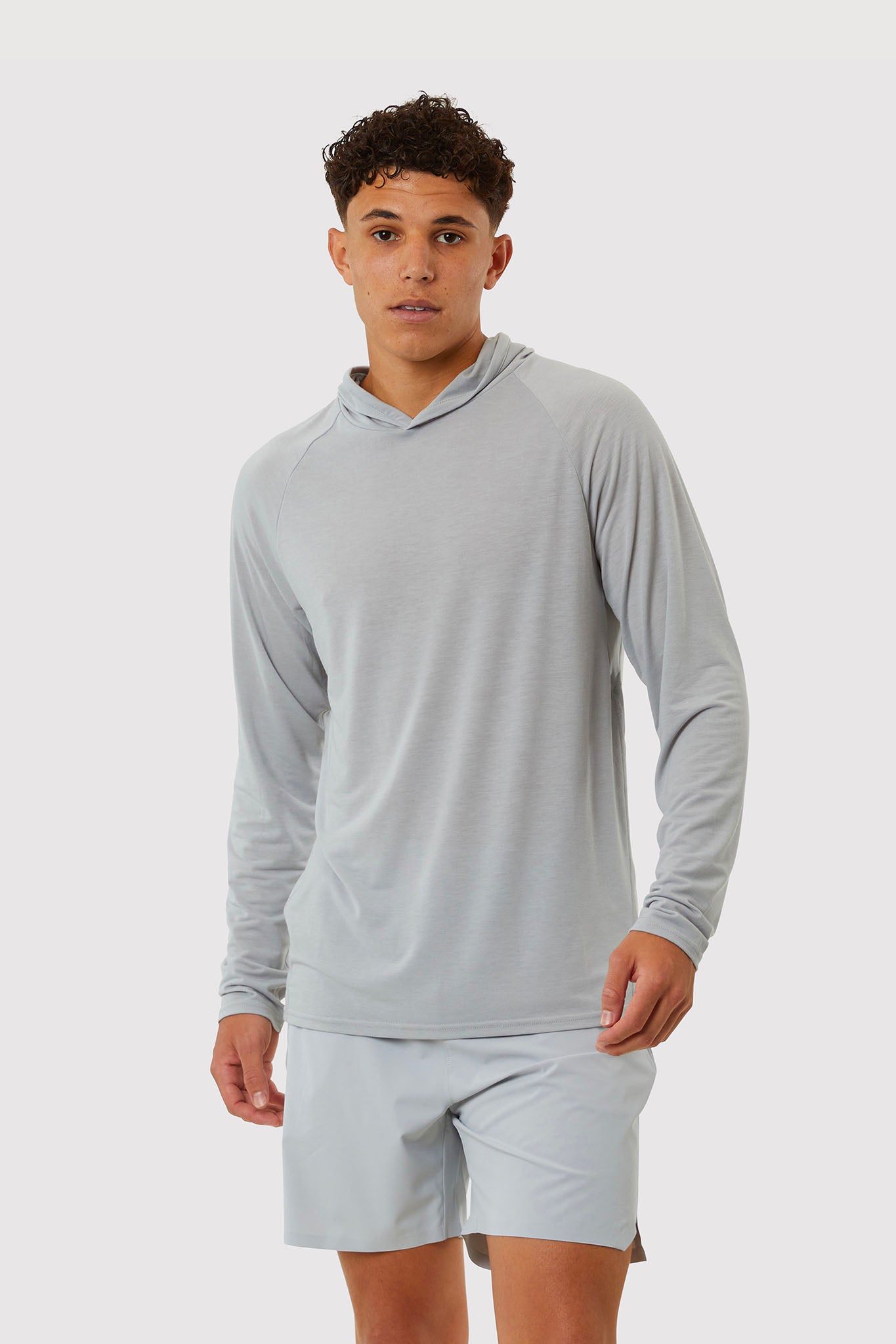 Person wearing a gray long-sleeve shirt and shorts on a white background