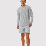 Man wearing a gray long-sleeve shirt and shorts on a white background