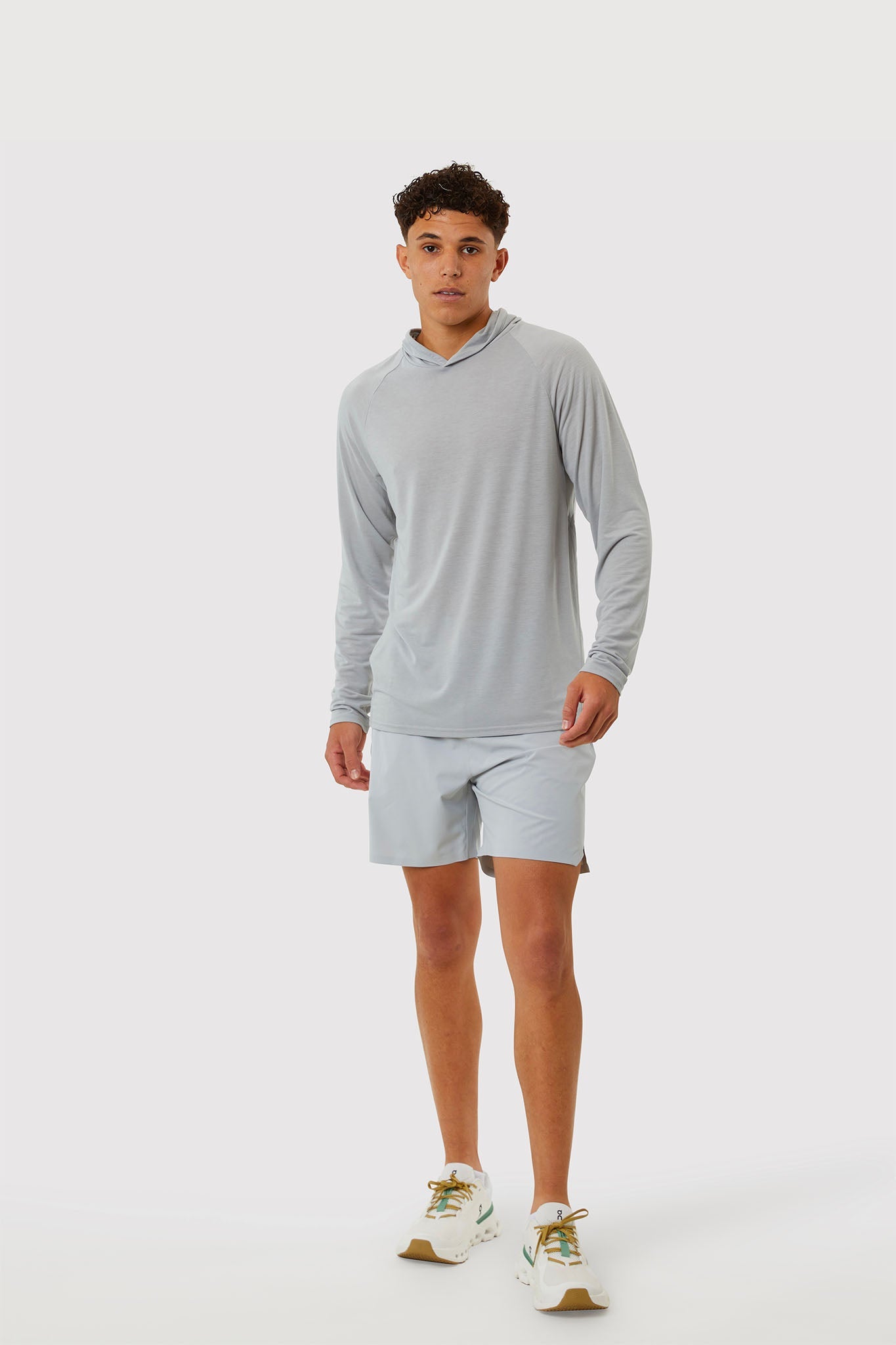 Man wearing a gray long-sleeve shirt and shorts on a white background