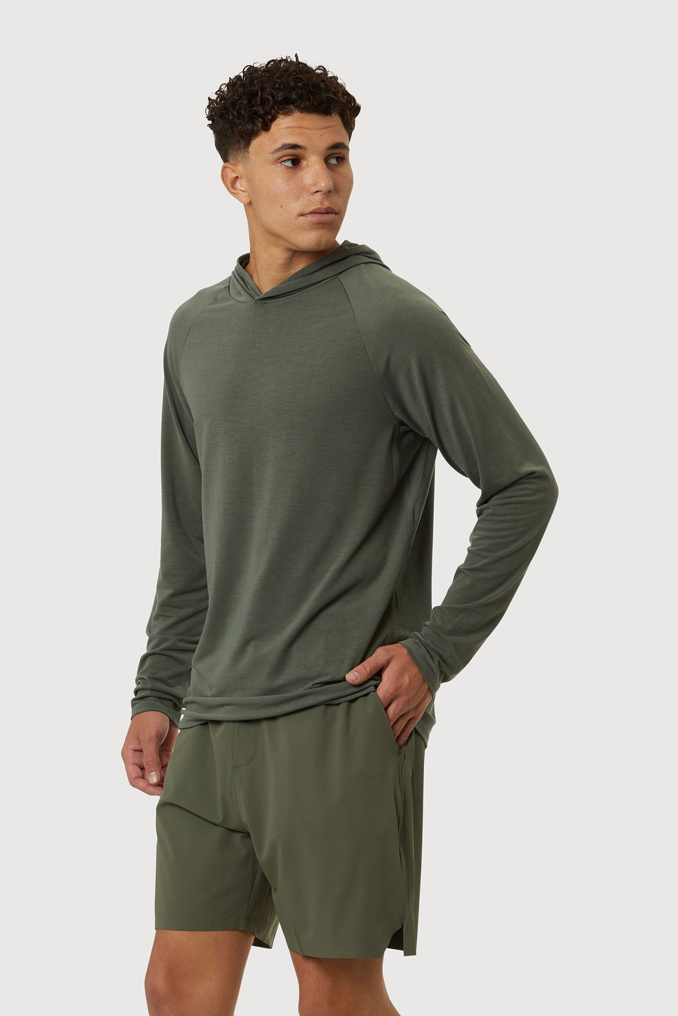 Man wearing a green hoodie and shorts on a white background