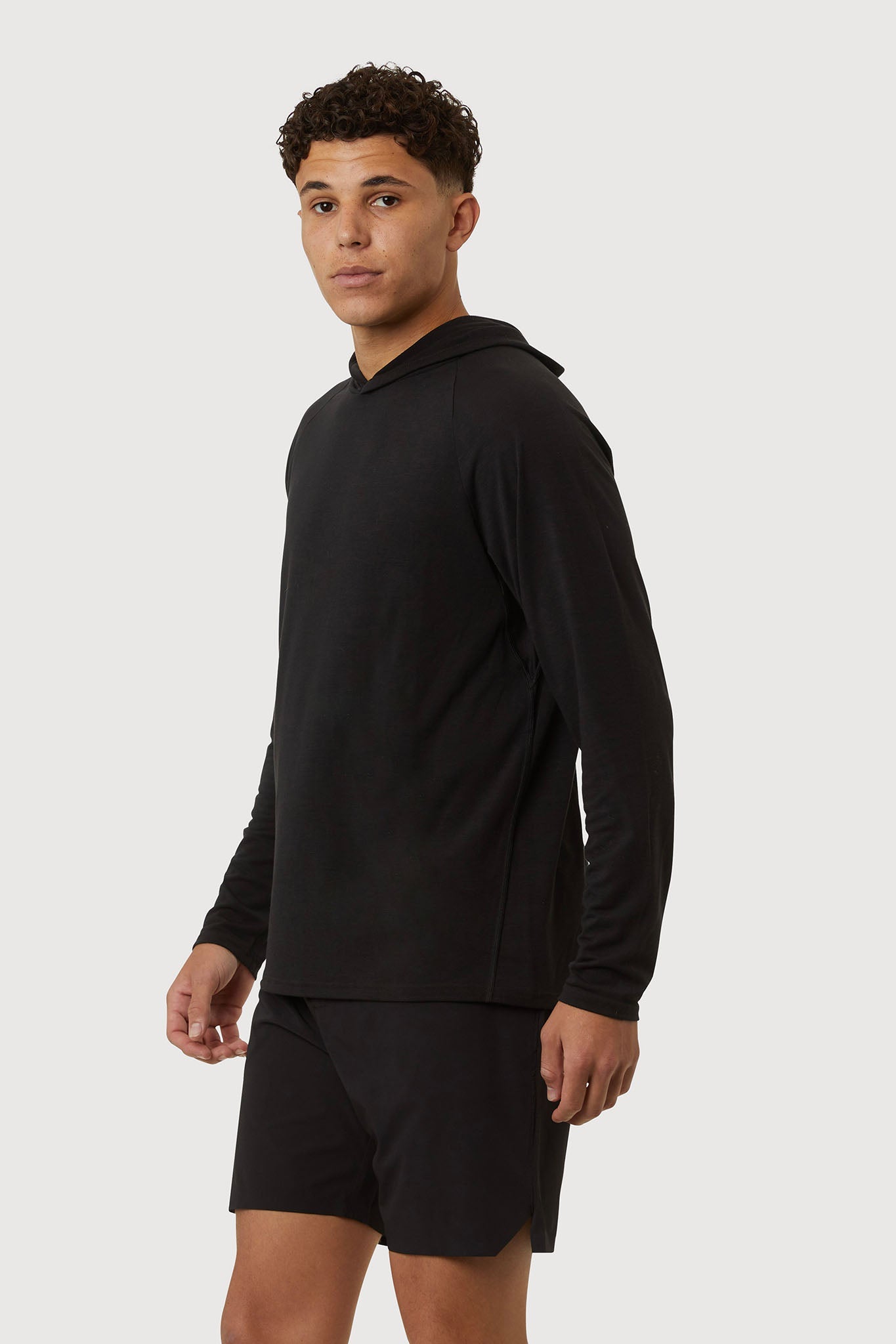 Man wearing a black hoodie and shorts on a white background