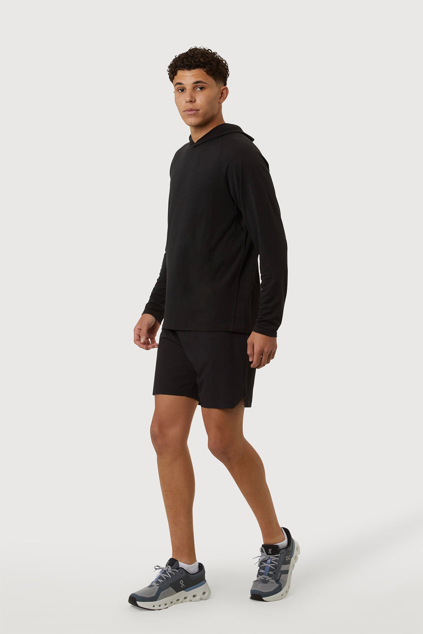 Person wearing a black long-sleeve shirt and shorts on a white background