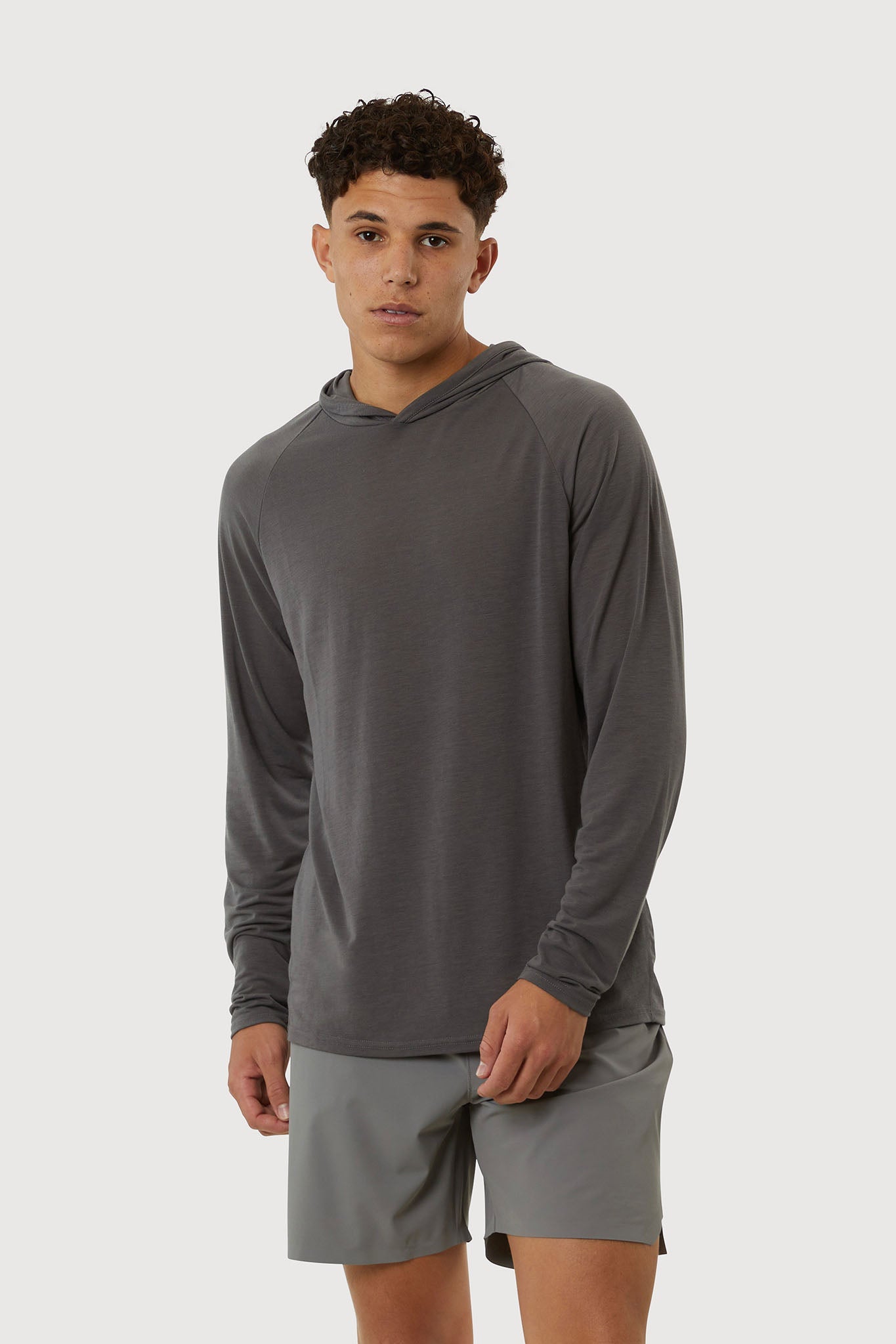 Man wearing a gray long-sleeve athletic shirt and shorts on a white background