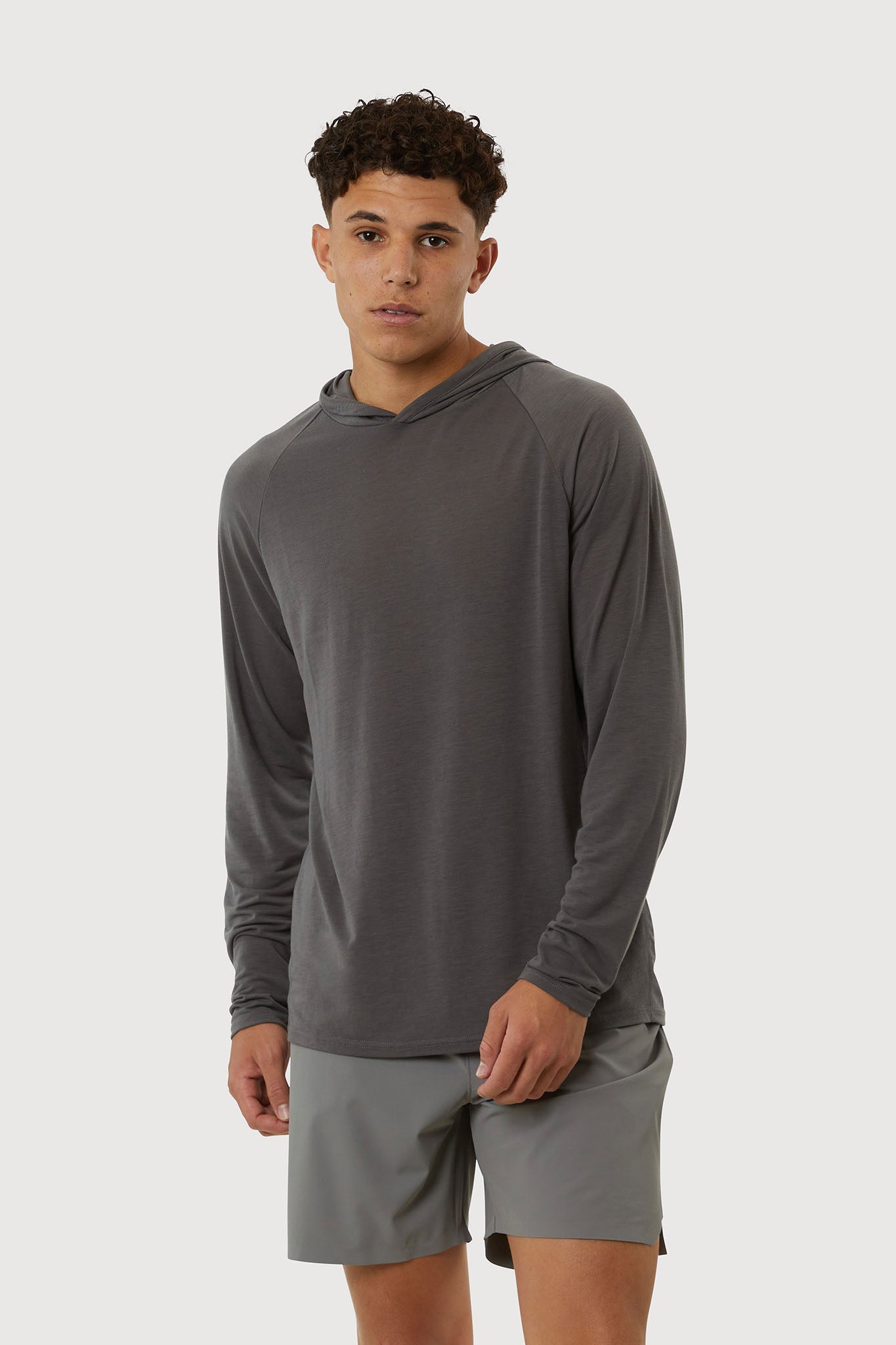 Man wearing a gray long-sleeve athletic shirt and shorts on a white background