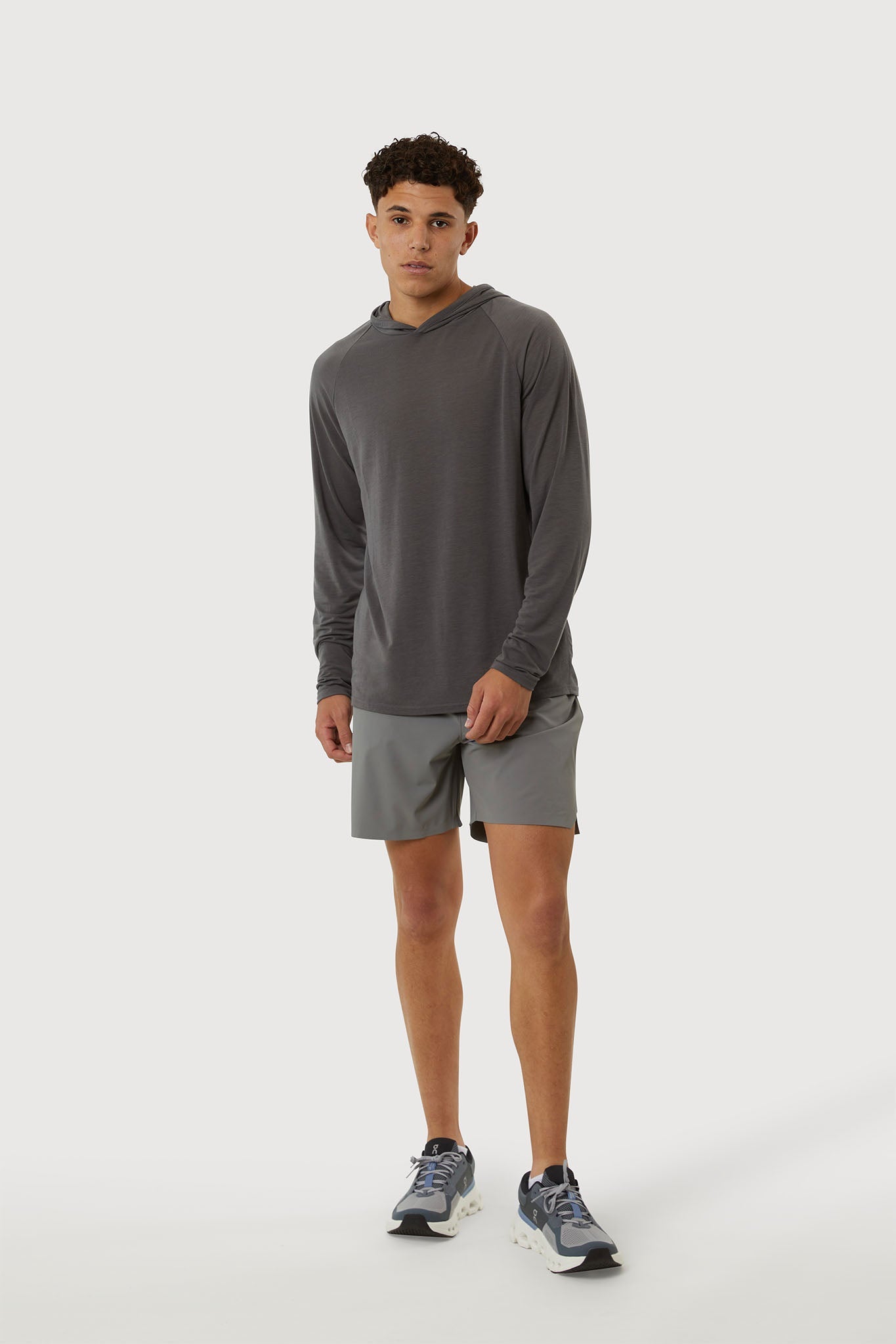 Man wearing a gray long-sleeve shirt and shorts on a white background