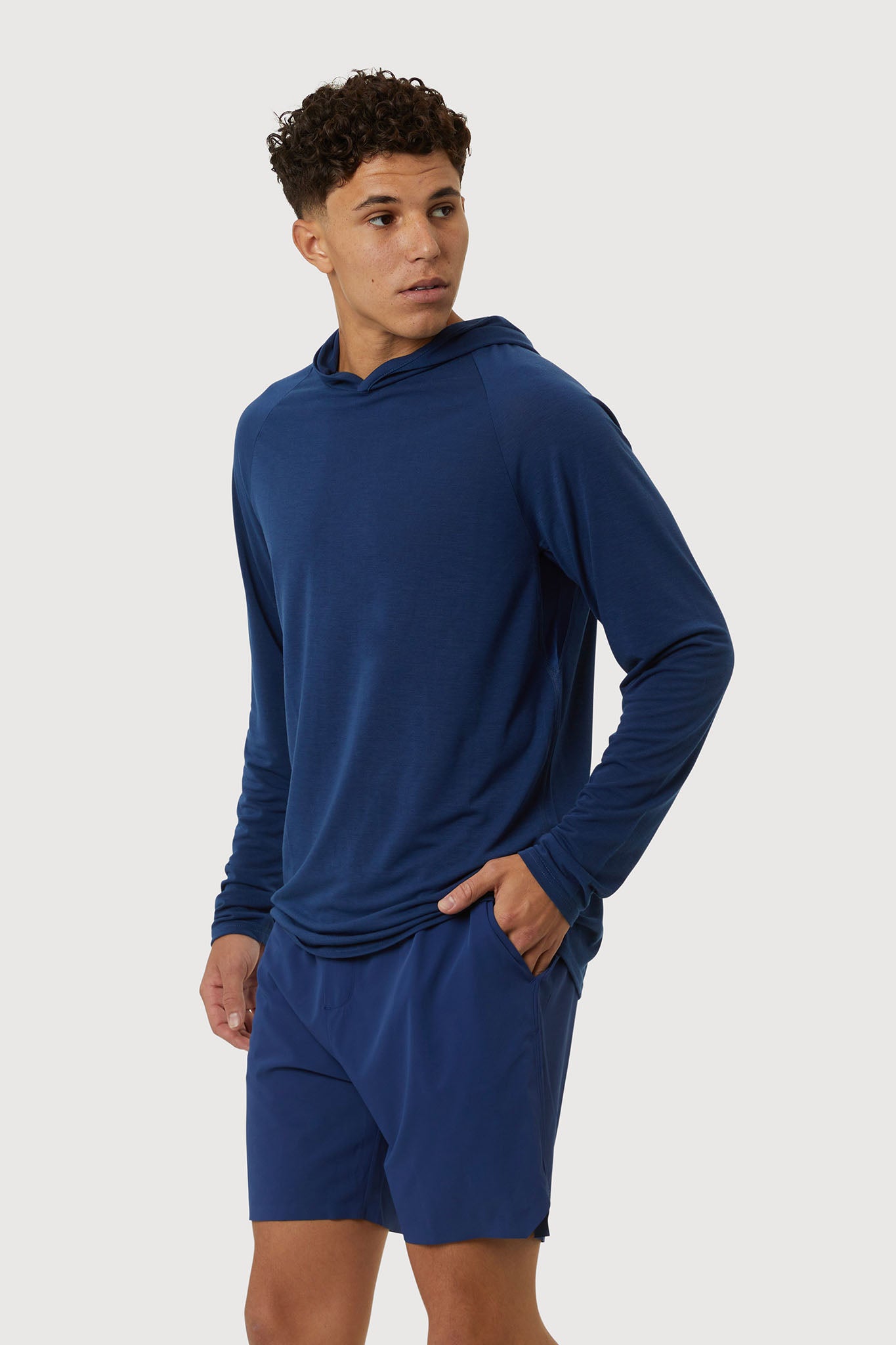 Man wearing a blue hoodie and shorts on a white background