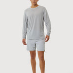 Person wearing a gray long-sleeve shirt and light gray shorts on a white background