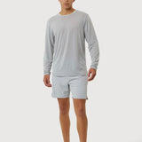 Person wearing a gray long-sleeve shirt and light gray shorts on a white background