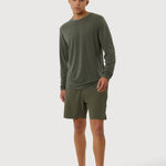 Man wearing a green long-sleeve shirt and shorts on a white background