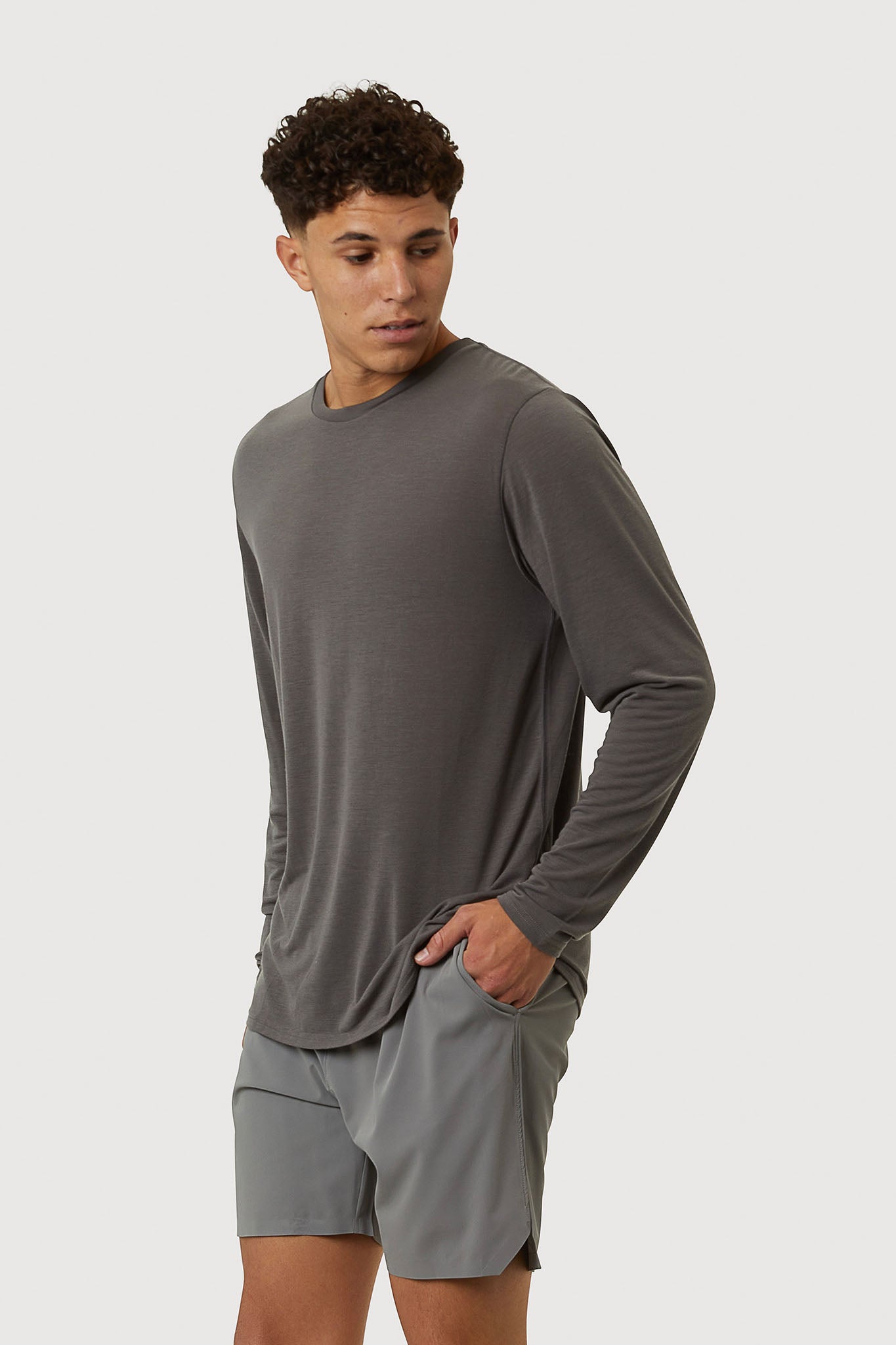 Man wearing a gray long-sleeve shirt and shorts on a white background