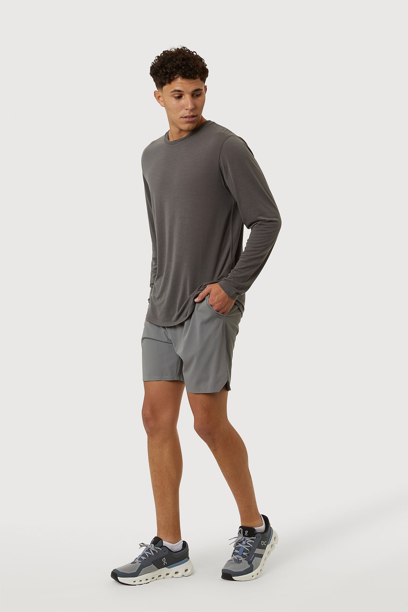 Man wearing a gray long-sleeve shirt and shorts on a white background