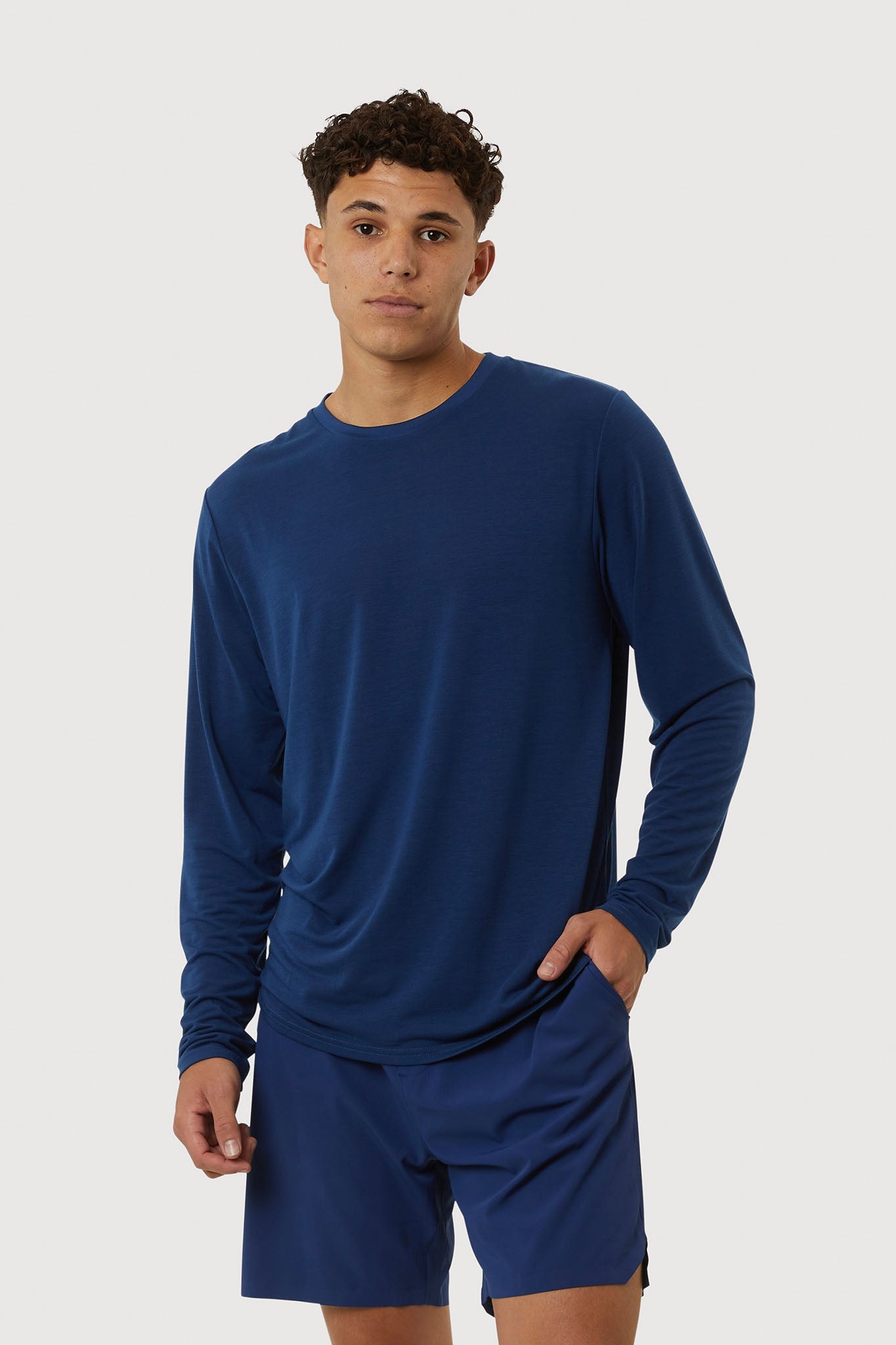 Man wearing a blue long-sleeve shirt and shorts on a white background