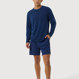 Person wearing a blue long-sleeve shirt and shorts on a white background