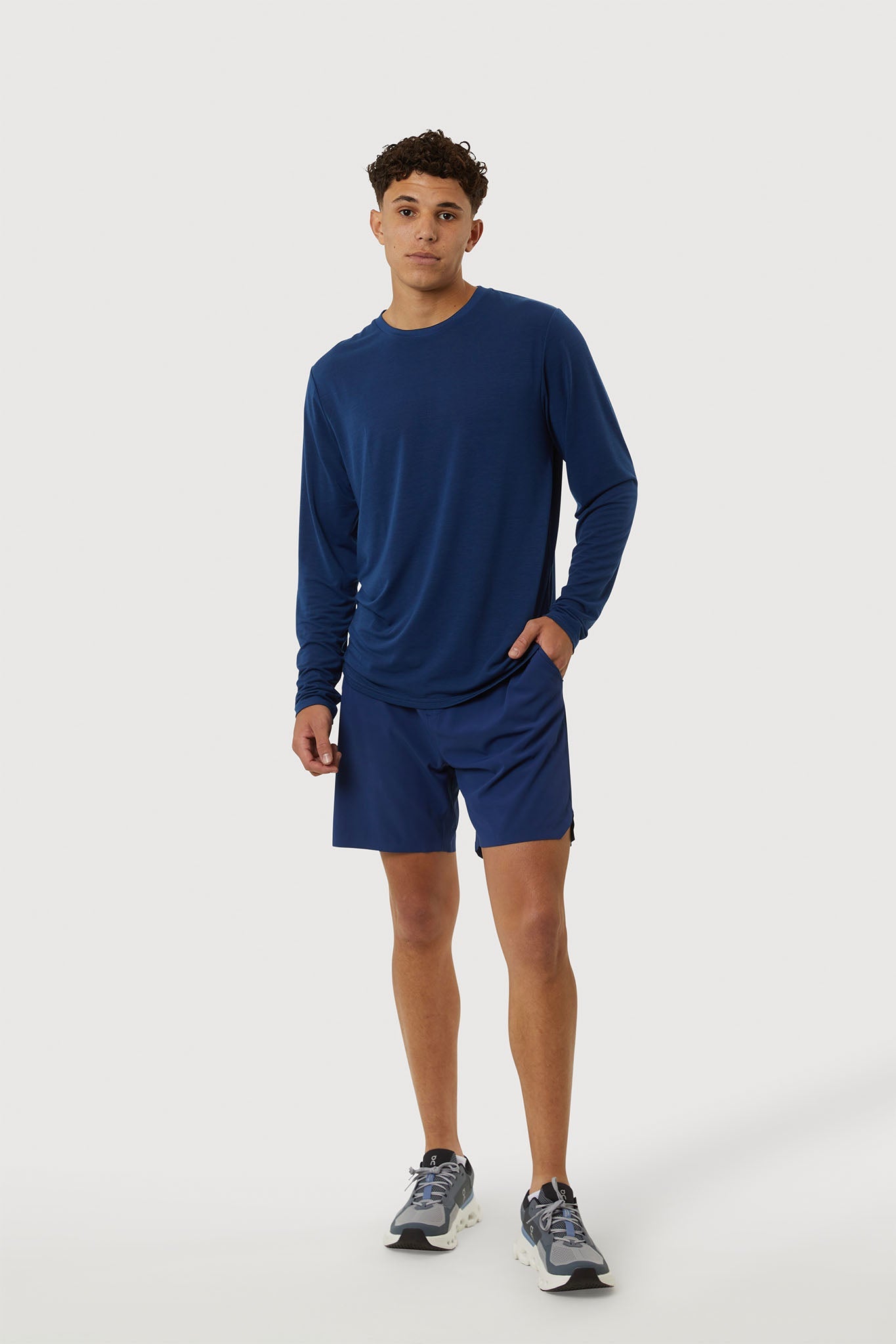 Person wearing a blue long-sleeve shirt and shorts on a white background