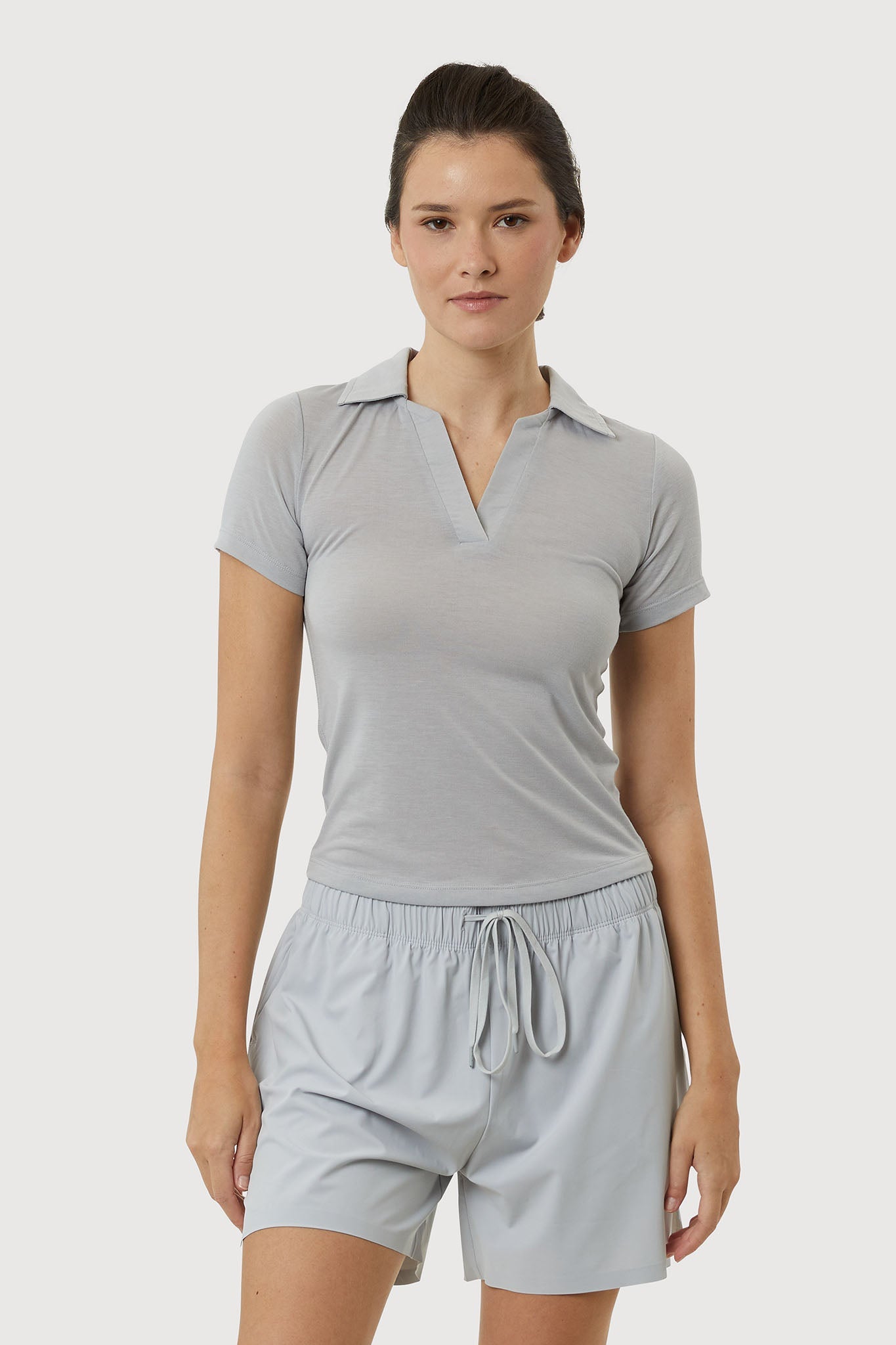 Woman wearing a gray short-sleeve top and shorts set on a white background