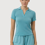 Woman wearing a teal polo shirt and shorts set on a white background