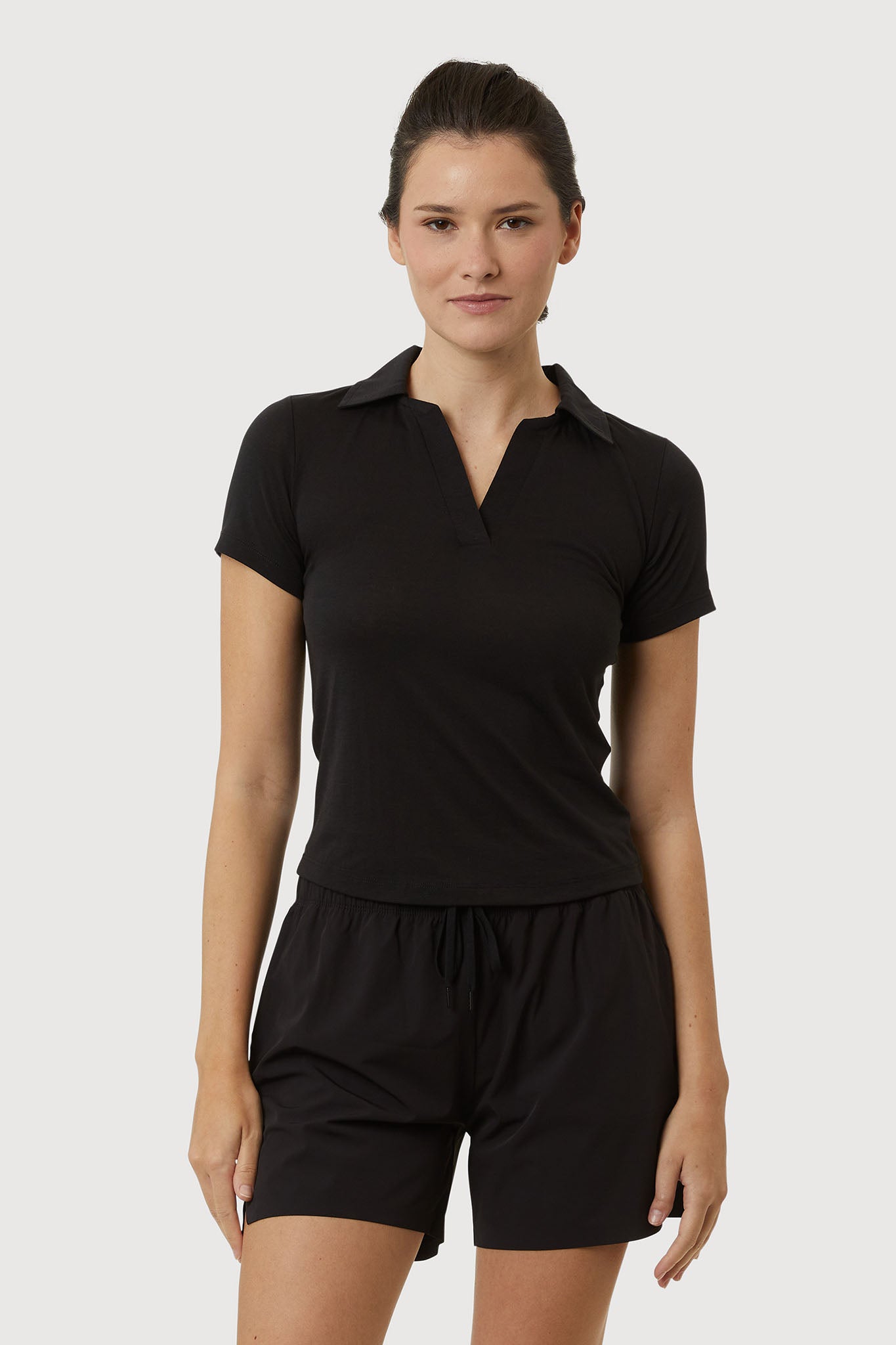 Woman wearing a black polo shirt and shorts on a white background