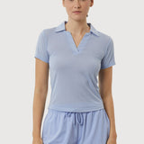 Woman wearing a light blue polo shirt and shorts set on a white background