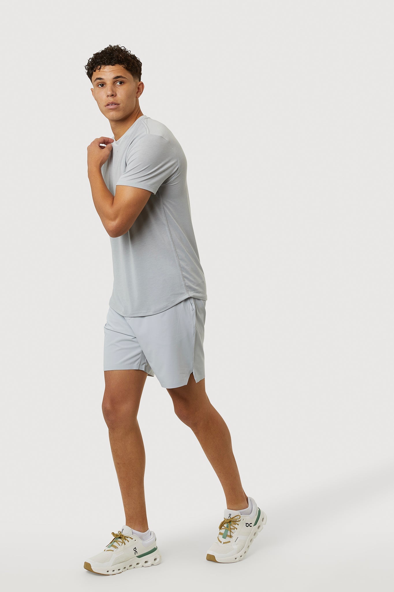 Man wearing a light gray t-shirt and shorts on a white background