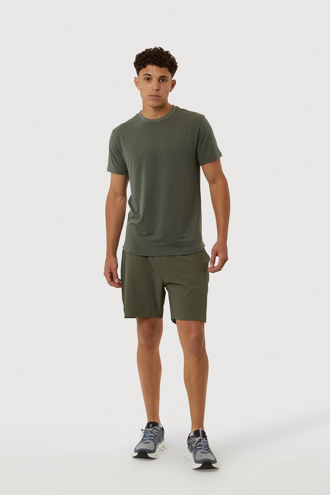Man wearing a green t-shirt and shorts on a white background