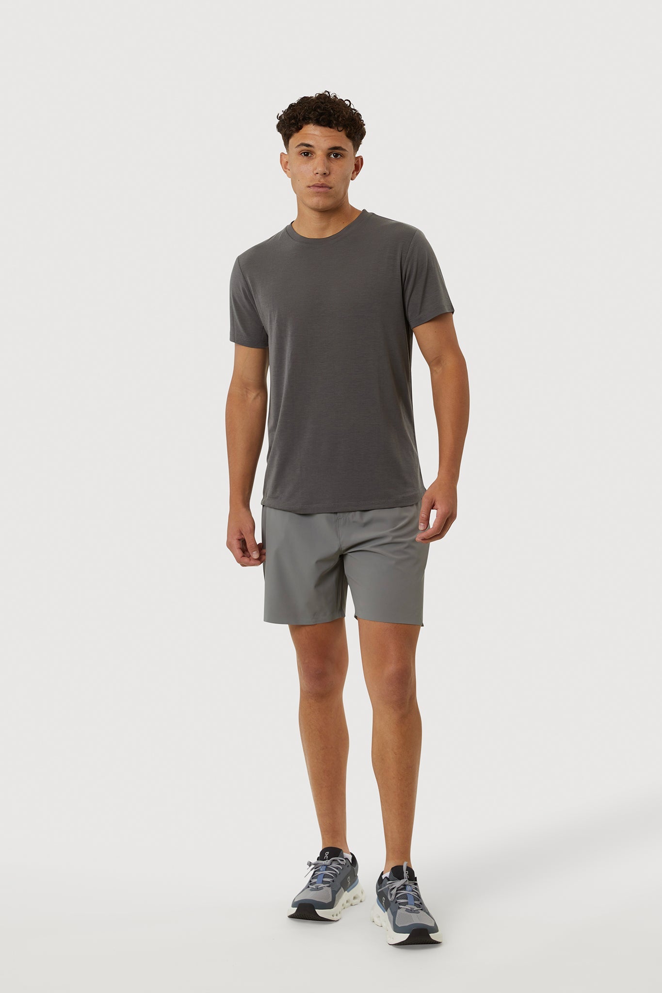 Man wearing a gray t-shirt and shorts on a white background
