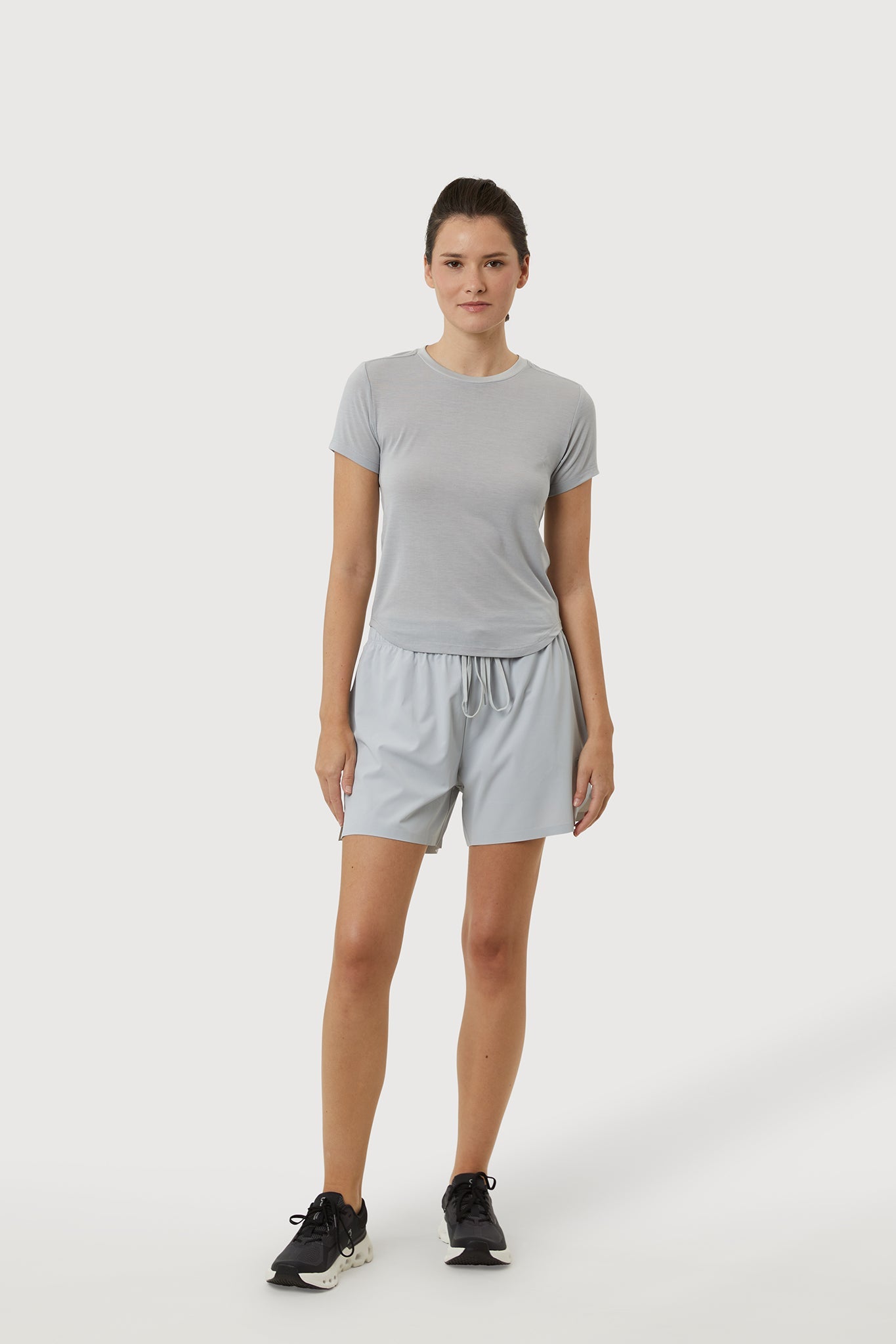 Woman wearing a gray t-shirt and shorts on a white background