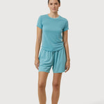 Woman wearing a teal t-shirt and shorts set on a white background