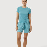 Woman wearing a teal t-shirt and shorts set on a white background