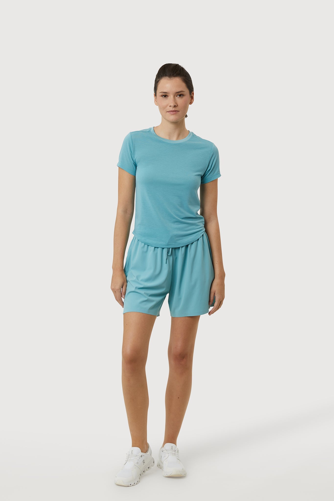 Woman wearing a teal t-shirt and shorts set on a white background