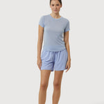 Woman wearing a light blue t-shirt and shorts on a white background