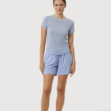 Woman wearing a light blue t-shirt and shorts on a white background