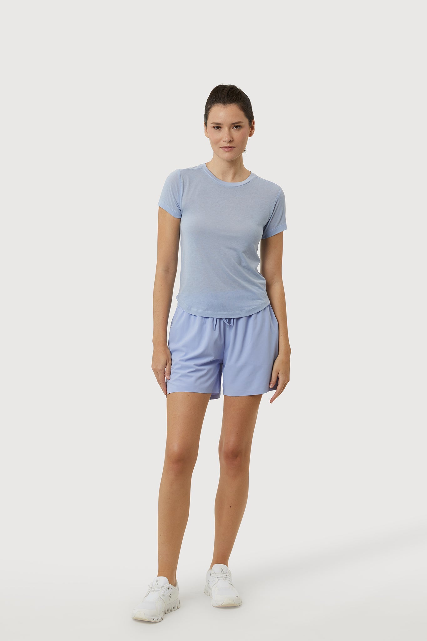 Woman wearing a light blue t-shirt and shorts on a white background