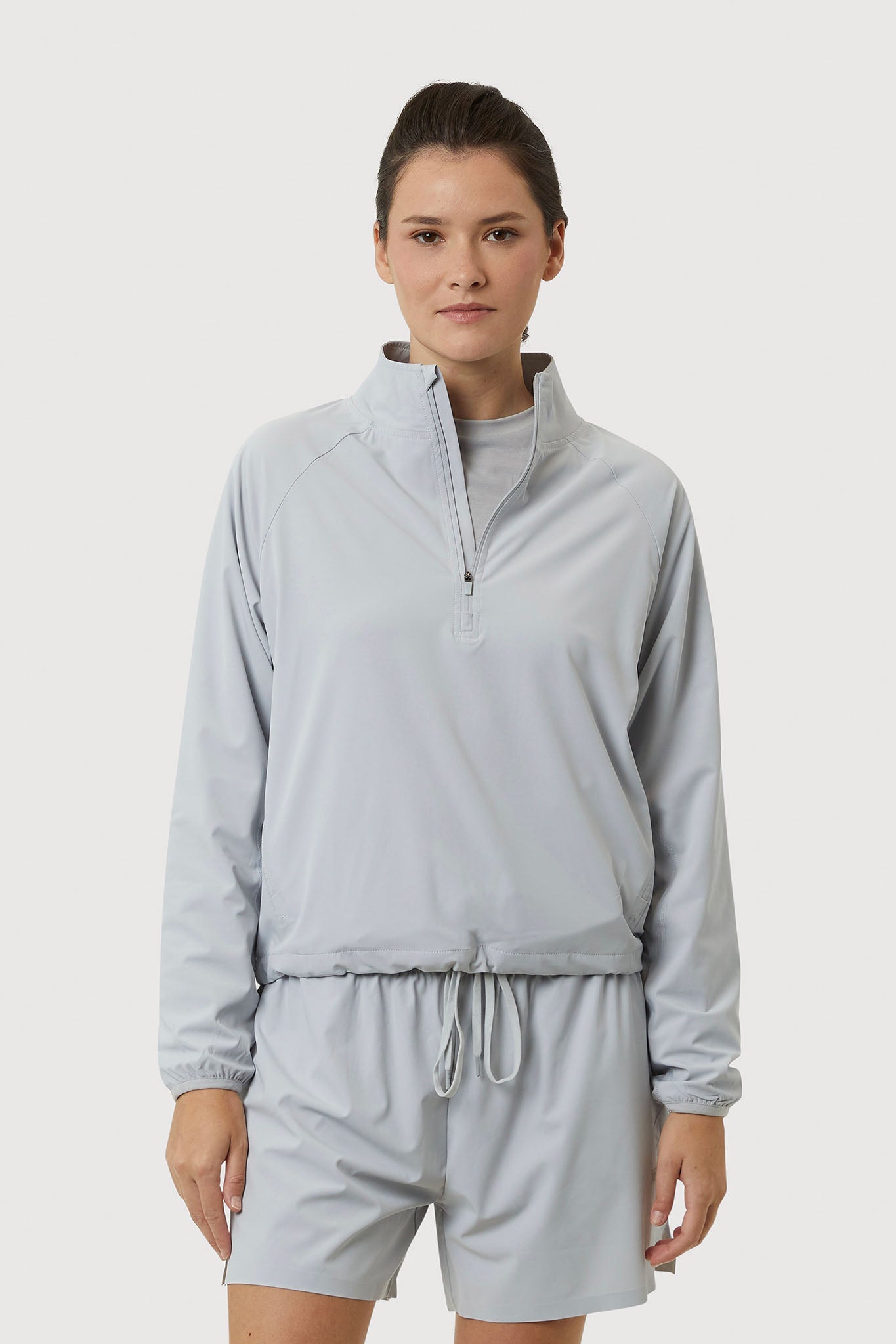 Woman wearing a light gray tracksuit on a white background