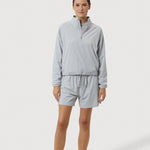 Person wearing a light gray tracksuit on a white background