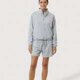 Person wearing a light gray tracksuit on a white background