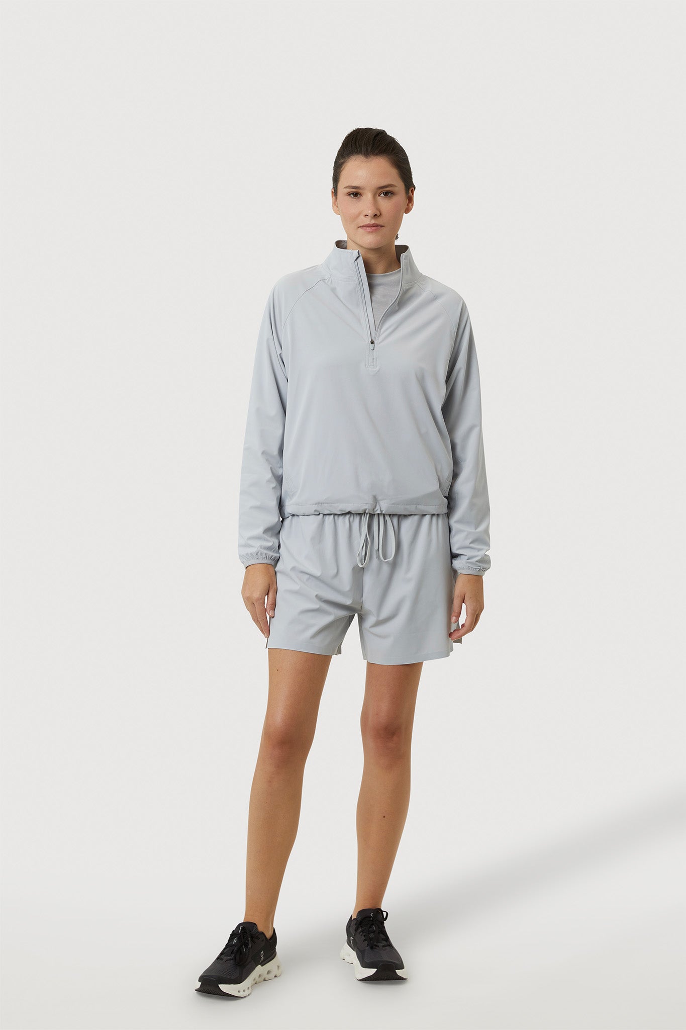 Person wearing a light gray tracksuit on a white background