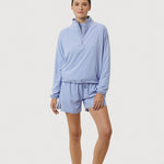 Person wearing a light blue outfit with shorts on a white background