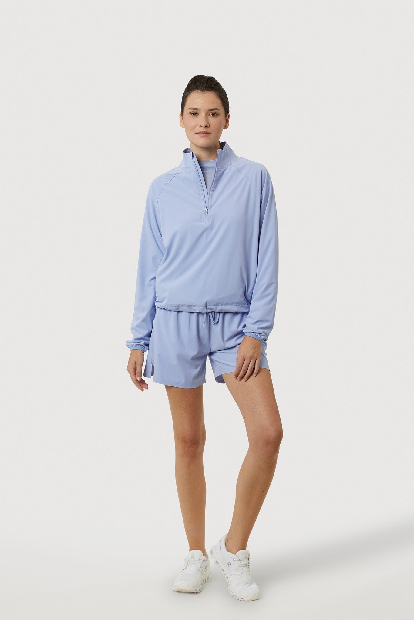 Person wearing a light blue outfit with shorts on a white background