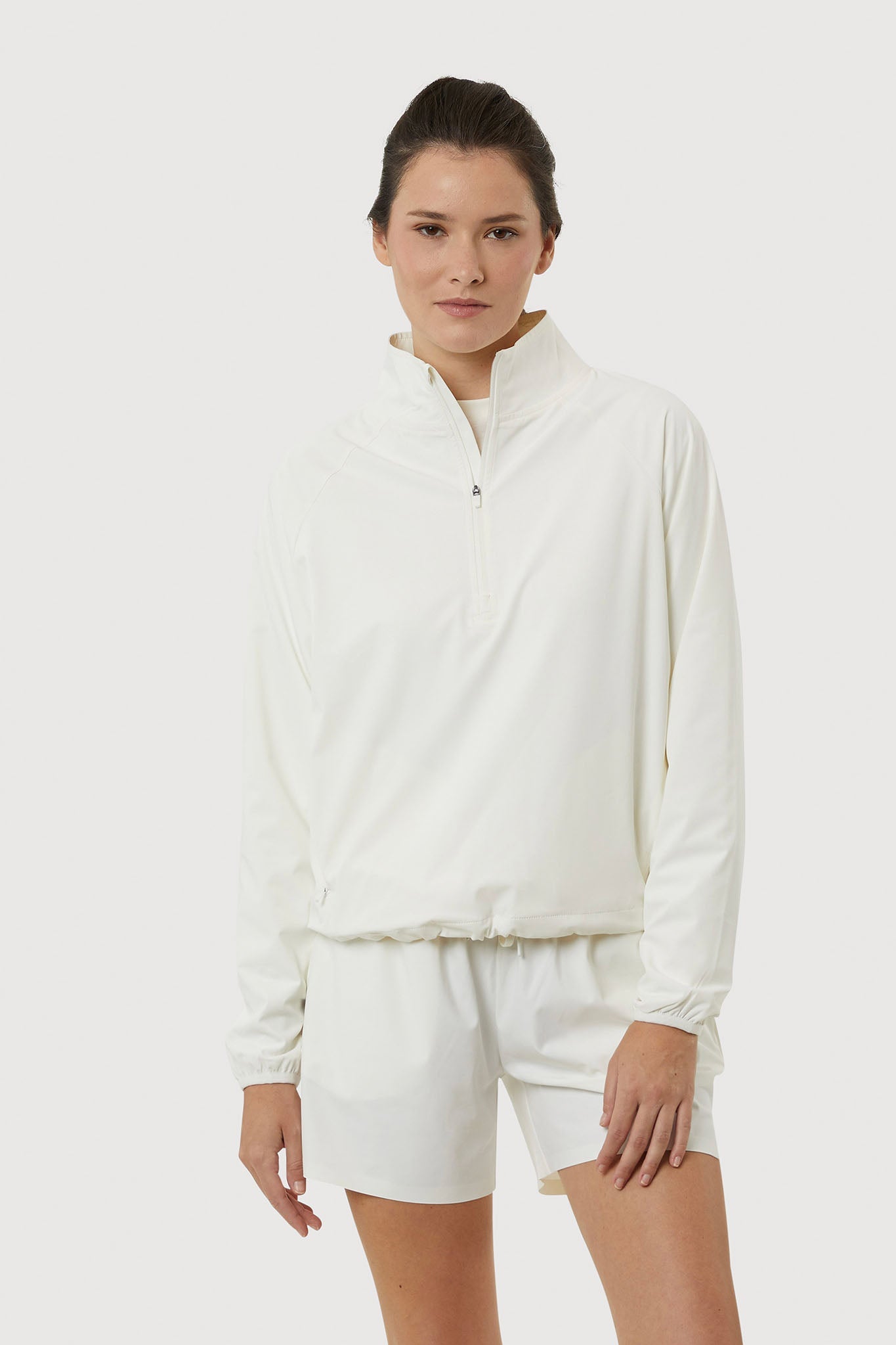 Person wearing a white zip-up sweatshirt and shorts on a light gray background