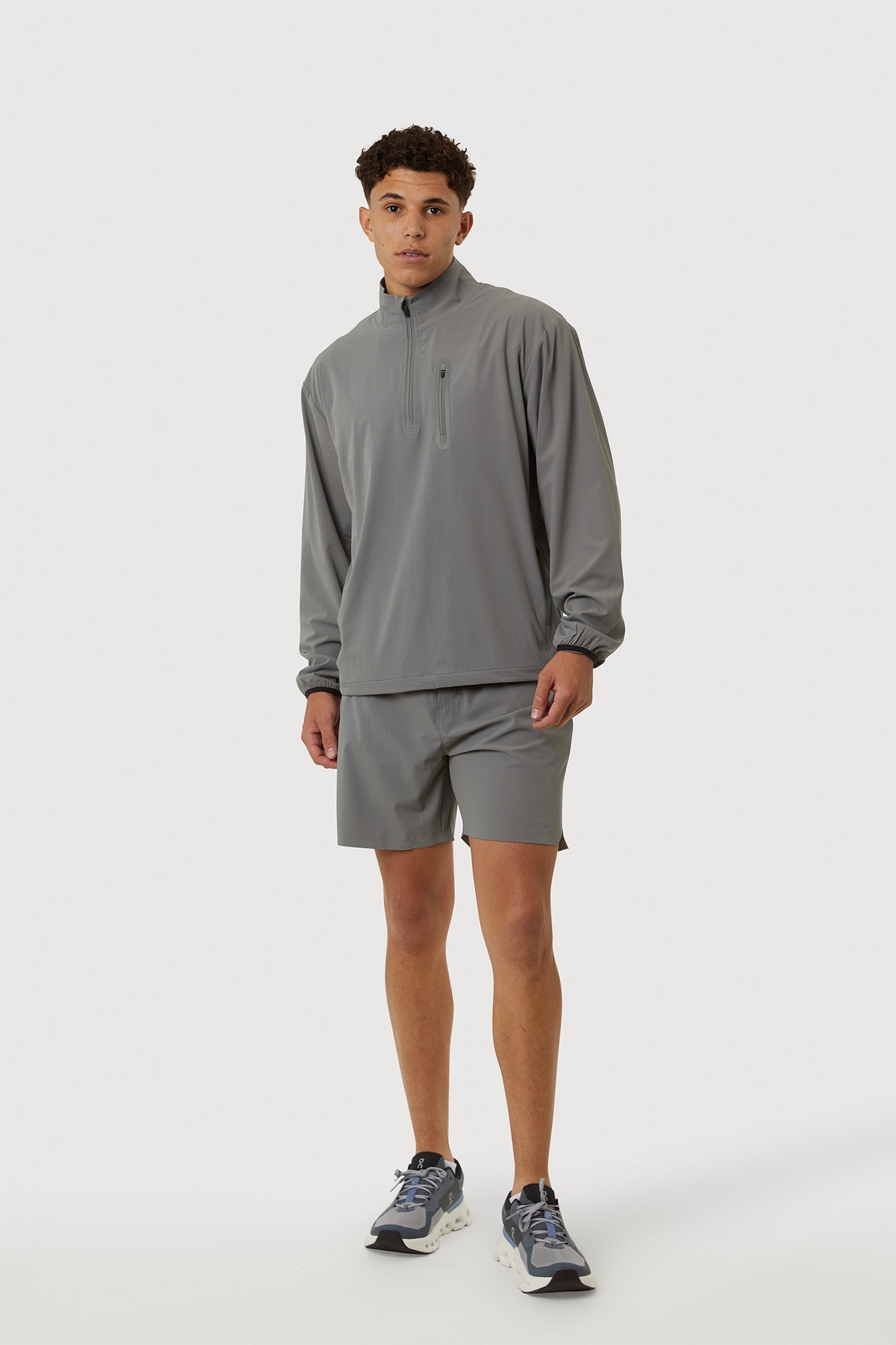 Person wearing a gray long-sleeve shirt and shorts on a white background
