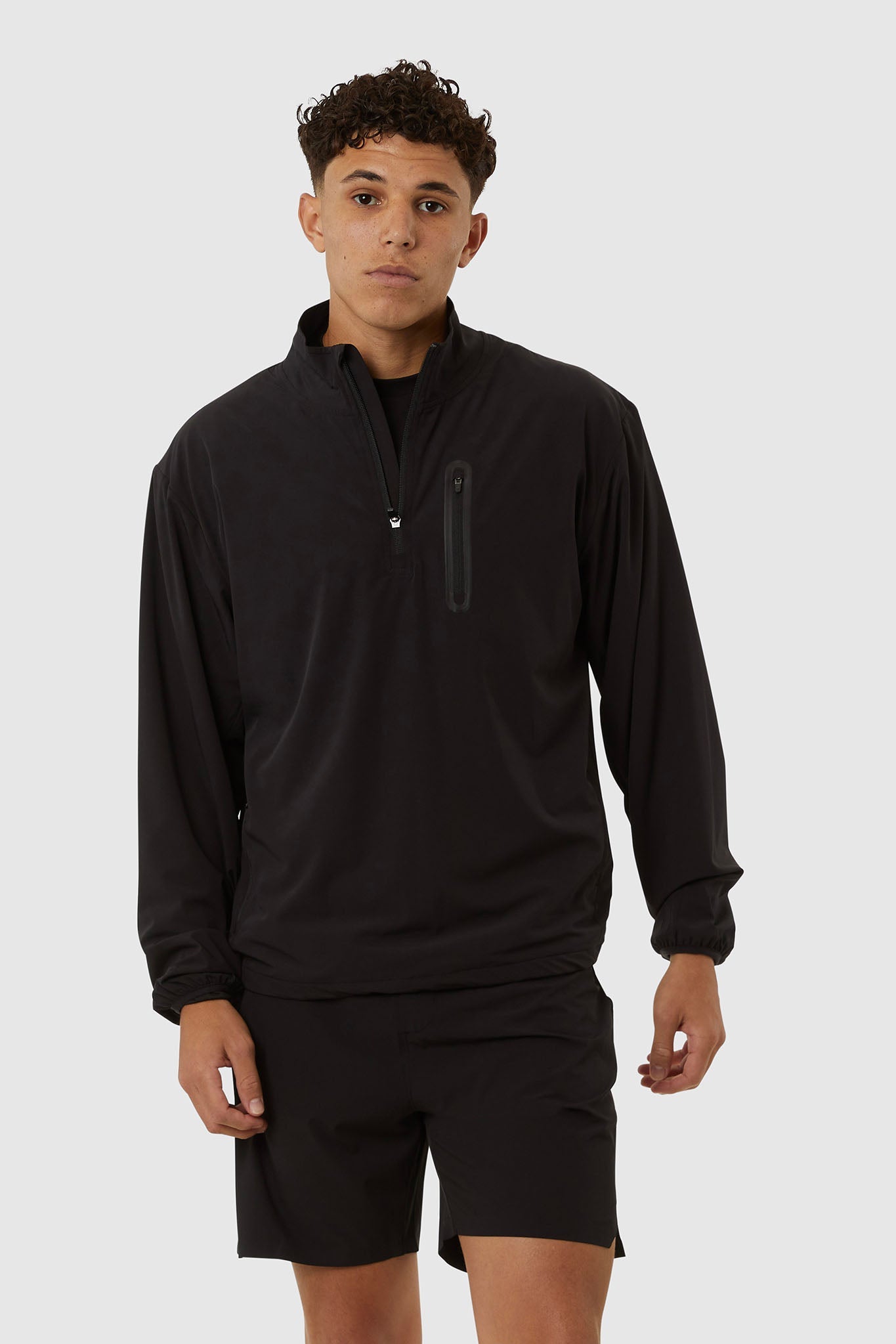 Person wearing a black long-sleeve athletic shirt and shorts on a white background