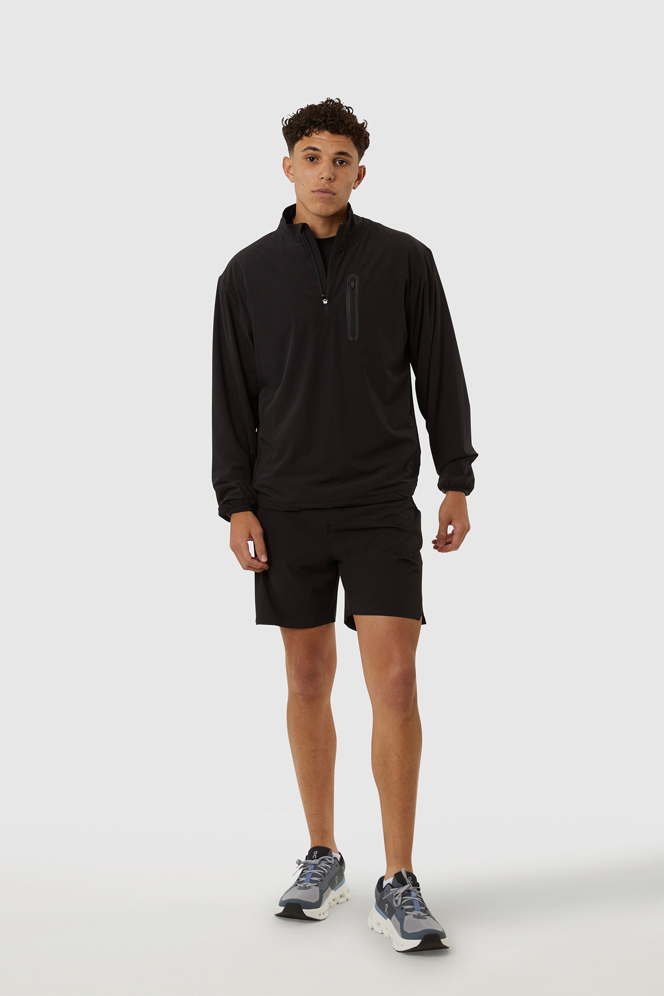 Person wearing a black long-sleeve athletic shirt and shorts on a white background