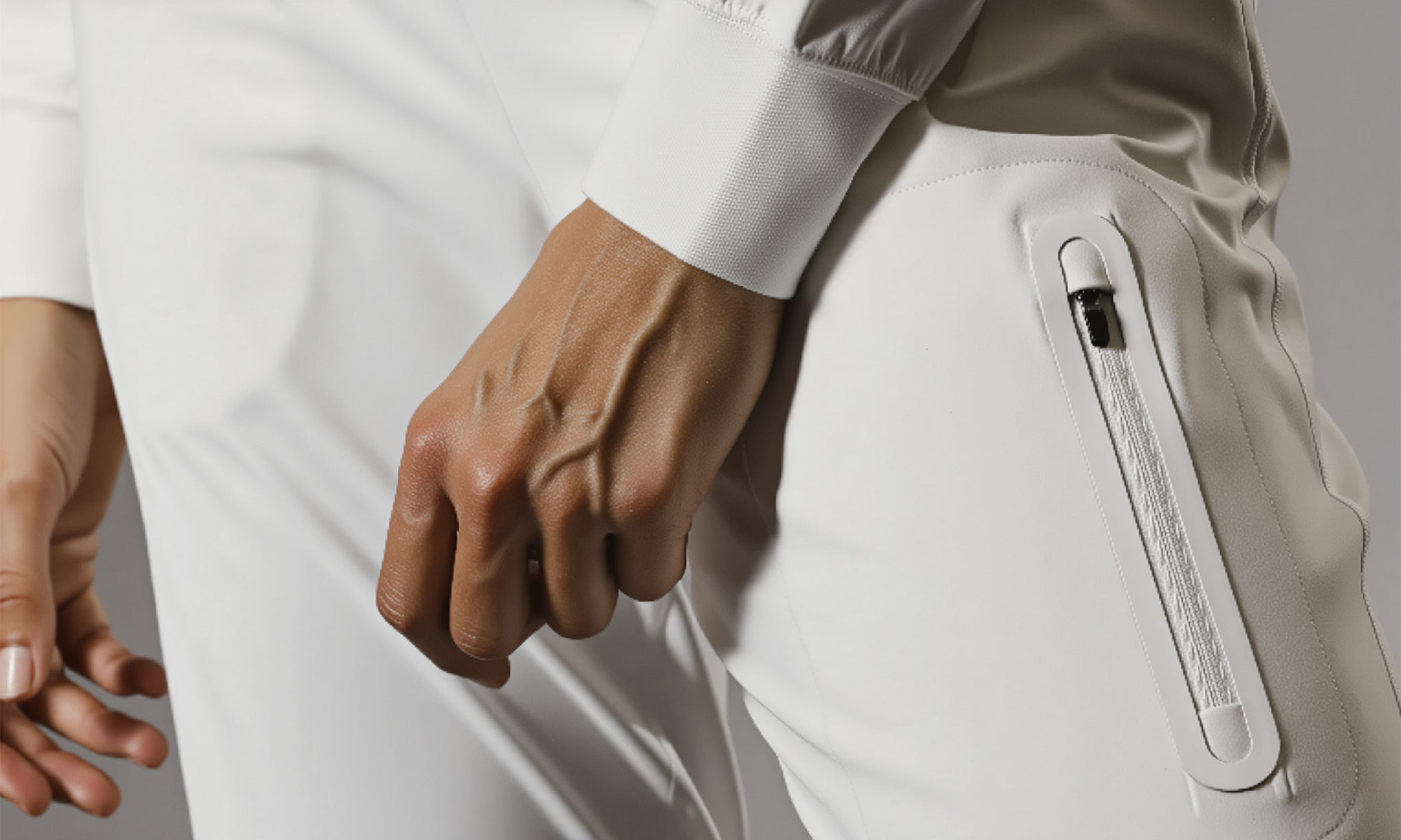 Close-up of a person wearing a white outfit with a pocket device on a gray background