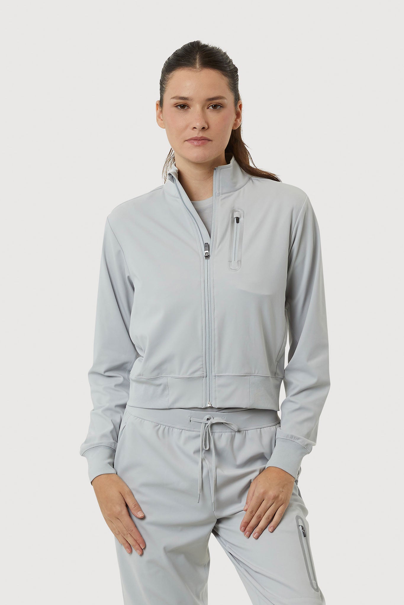 Woman wearing a light gray tracksuit on a white background