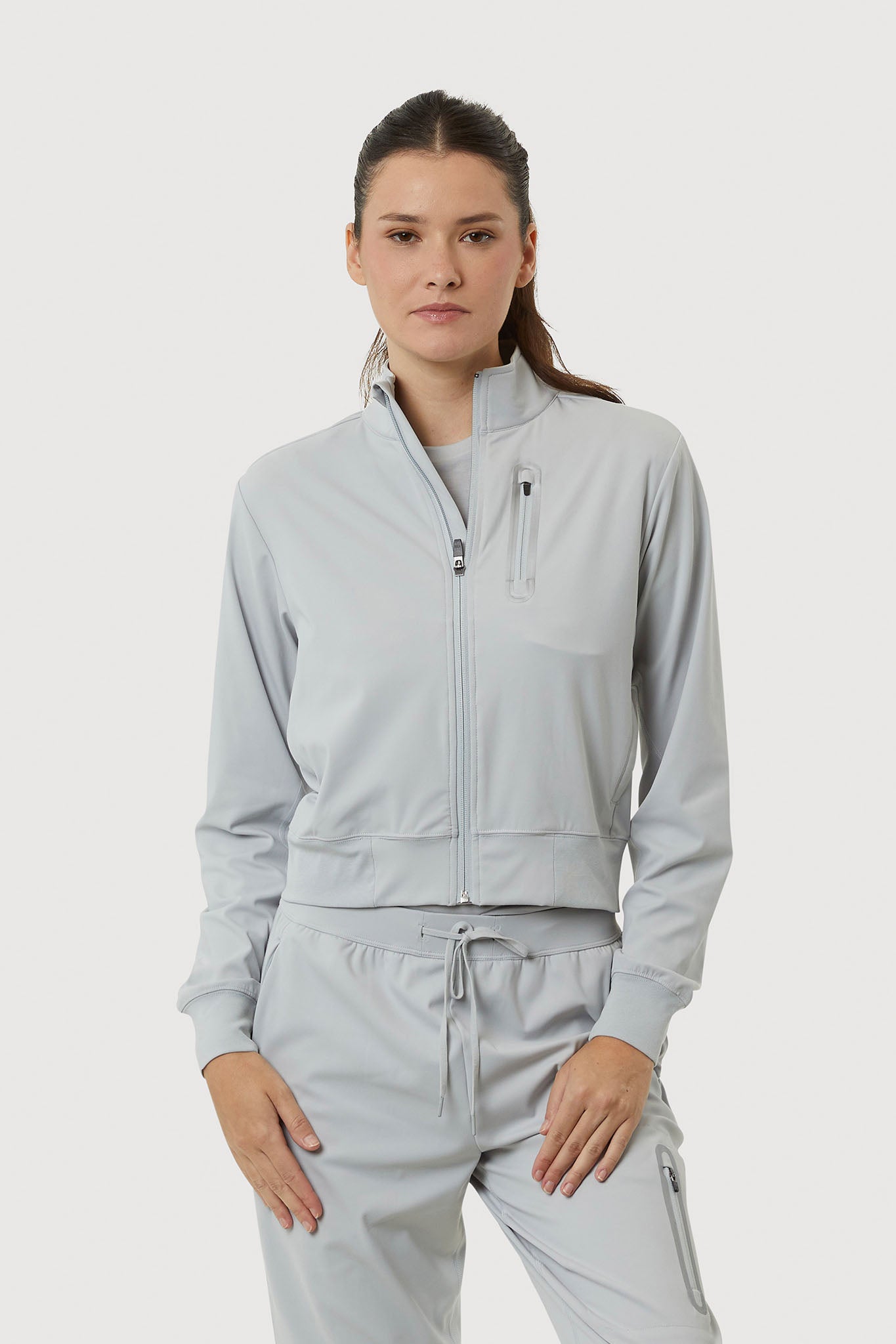 Woman wearing a light gray tracksuit on a white background