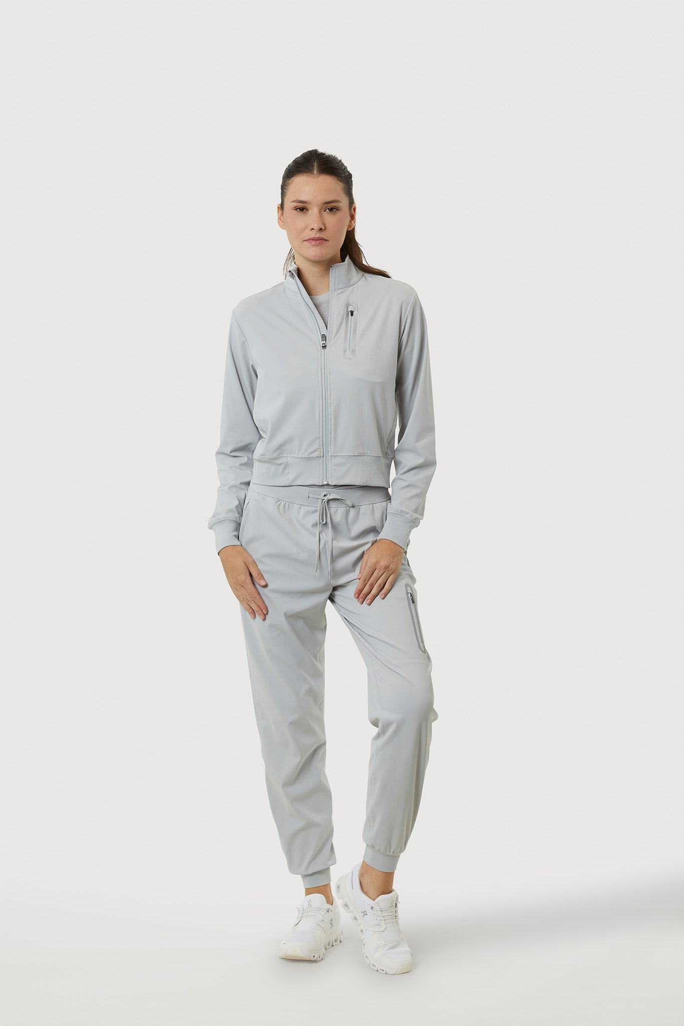 Person wearing a light gray tracksuit on a white background