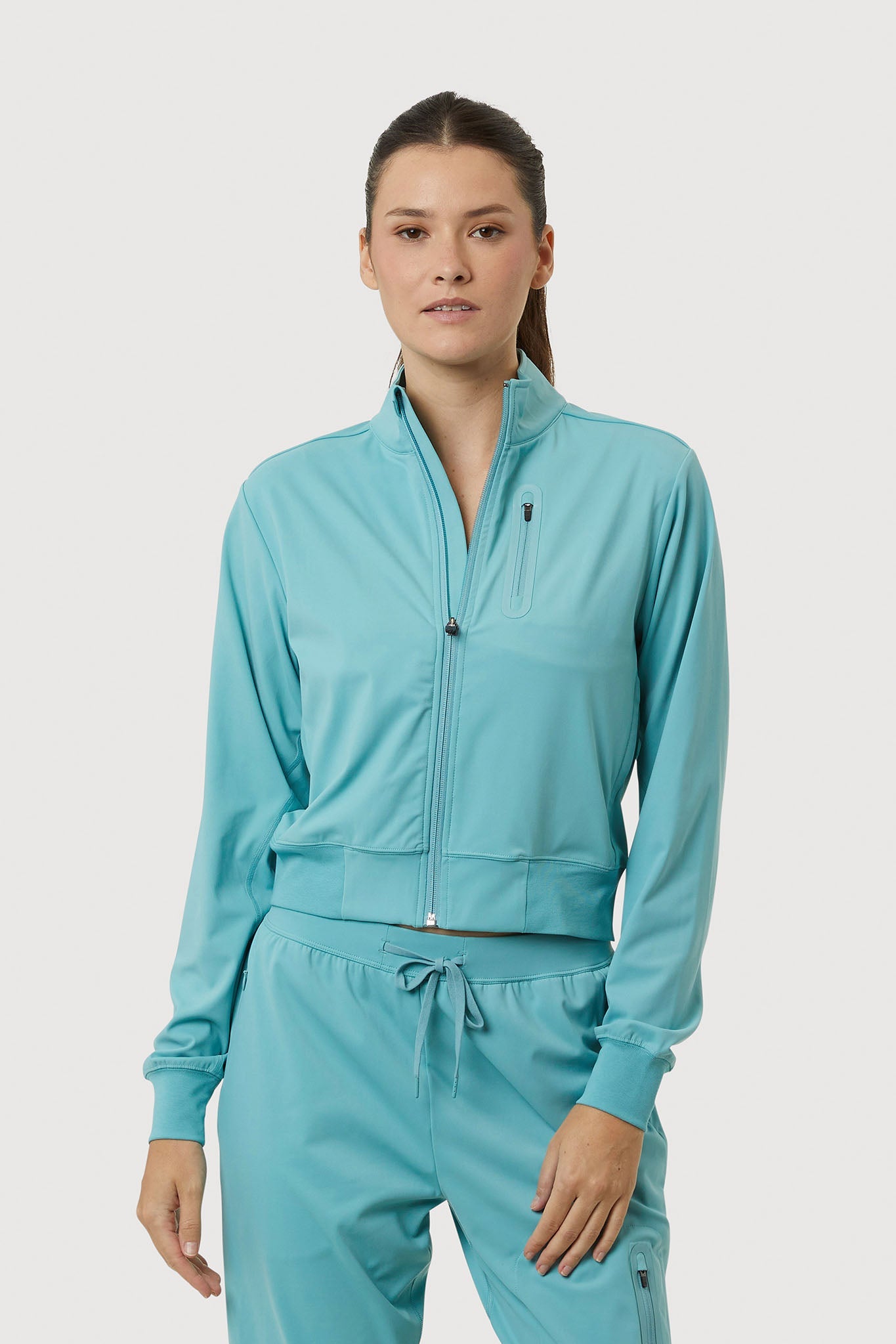 Woman wearing a teal tracksuit on a white background